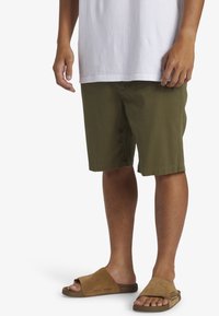 Olijfgroene shorts van katoen, met een losse pasvorm en een knielange snit. Gecombineerd met bruine instapsandalen met een zachte suède afwerking.