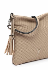 Beige perforierte Lederhandtasche mit schwarzem Besatz, silberner Schnalle und dekorativem Anhänger, der von der oberen Ecke hängt.