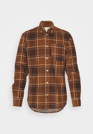 Camicia in velluto a coste marrone con motivo a quadri, dotata di colletto button-down, taschino sul petto e accenti color marrone chiaro su sfondo scuro.