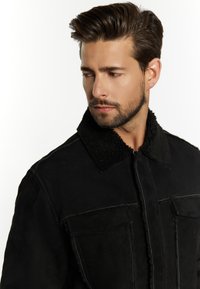 Schwarze, mit Schafsleder gefütterte Jacke mit einem strukturierten Kragen, Vorder pockets und sichtbaren Nähten, die ein mattes Finish und ein elegantes Design zeigen.