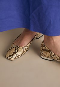 Snekkskinn-print lave hæler i beige og brune nyanser med firkantet tådesign og en liten metallisk detalj på hælen.
