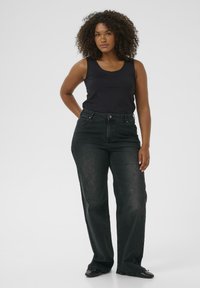 Black denim jeans with a straight-leg cut, high waist, and subtle fading. Paired with a fitted black tank top and black shoes.