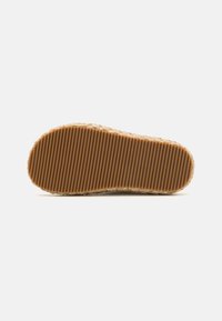 Rubber outsole features deep grooves for traction. Braid-like texture at the edge, with a natural beige color emphasizing durability and grip.