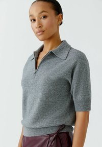 Grijze sweater met korte mouwen, een kraag en een halve rits aan de voorkant. Zachte textuur, geribbelde zoom en een getailleerde pasvorm.