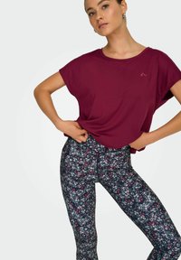Maroon kortärmad topp kombinerad med marinblå blommiga leggings. Leggingsen har ett litet blommönster i rosa och vitt på en mörk bakgrund.