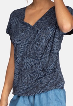 Top blu scuro a maniche corte con scollatura a V, caratterizzato da un motivo testurizzato e una vestibilità ampia, abbinato a pantaloni azzurri chiari.