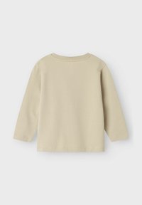 Pitkähihaista vaaleanbeigeä paitaa, joka on valmistettu pehmeästä puuvillasta, jossa on pyöreä pääntie ja suora helma hienovaraisilla ompelutiedoilla.