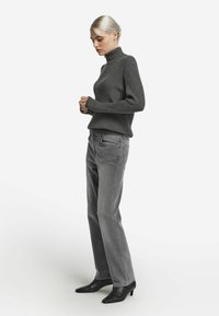 Grå ribbad polotröja, kombinerad med grå jeans med raka ben och svarta ankelboots med spetsig tå. Enkel, modern design med struktur.