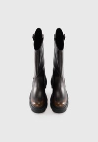 Une paire de bottes en cuir marron foncé, mi-mollet, avec des semelles épaisses noires, des tirettes et une finition lisse, présentée sur un fond clair.
