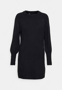 Svart stickad klänning med lång puffärm, texturerade ribbade manschetter och dekorativa pärlaccentuer kring halsringningen.