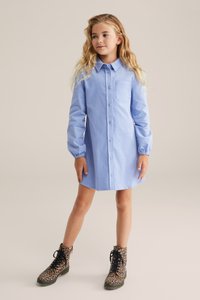 Rochie cămașă de un albastru deschis, cu un buzunar pe piept, mâneci lungi și manșete încrețite, asortată cu cizme cu imprimeu de leopard în culori negre și maro.