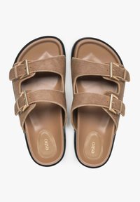 Brown fuzzy slide sandals with two adjustable straps and gold buckles. Soft inner sole with a smooth finish and a contrasting black outer sole.