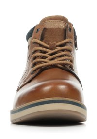 Zapato de cuero marrón con una parte superior texturizada, punta redonda, suela beige con una franja azul y un detalle de cordones visible. Ojal de metal incluido.