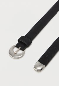 Čierny semišový opasok so striebornou kruhovou sponou a kovovým hrotom. Pás má hladký povrch a jemné stehy.