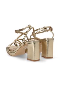 Sandalias de tacón alto metálico dorado con tacón cuadrado, que cuentan con tiras entrelazadas y una textura suave en la parte superior y el tacón.