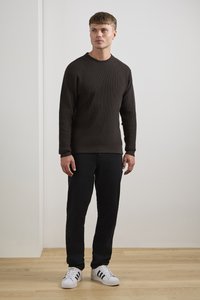 Dark brown ribbed knit sweater, black pants, and white sneakers with black stripes. Smooth texture, crew neck, and fitted design.