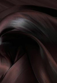 Tejido de satén en marrón oscuro con un brillo sutil, que muestra una textura suave y fluida y una superficie lisa, con pliegues suaves y sombras.