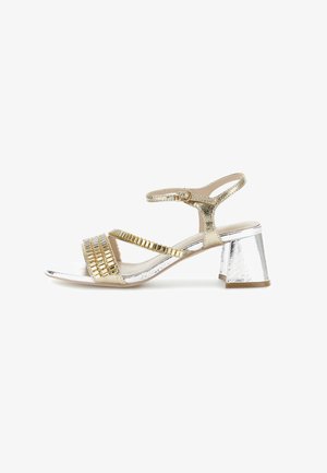 Gold and silver heeled sandal with a block heel, featuring crisscross straps adorned with metallic accents and a textured finish.