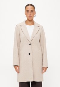 Lichtbeige wolmix jas met een geknipt kraag, twee zwarte knopen en lange mouwen. Heeft zijzakken en een rechte snit.