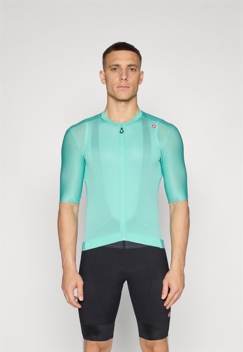 Kurzarm-Radtrikot in hellem Türkis, aus Mesh-Stoff, mit einem Reißverschluss vorne und tailliertem Schnitt. Getragen mit schwarzen Radshorts.
