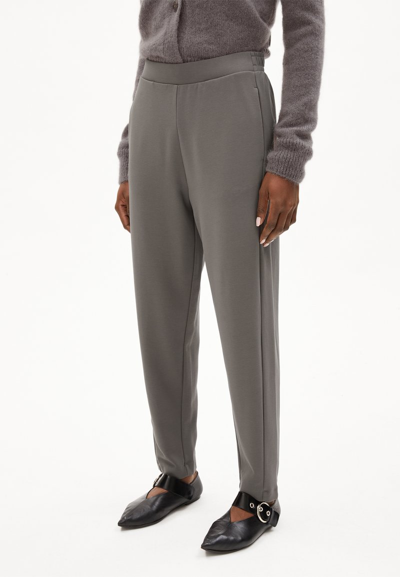 Grijze, op maat gemaakte broek met een gladde textuur en een elastische taille, met zijzakken en een taps toelopende pasvorm. Draag met zwarte puntige flats.