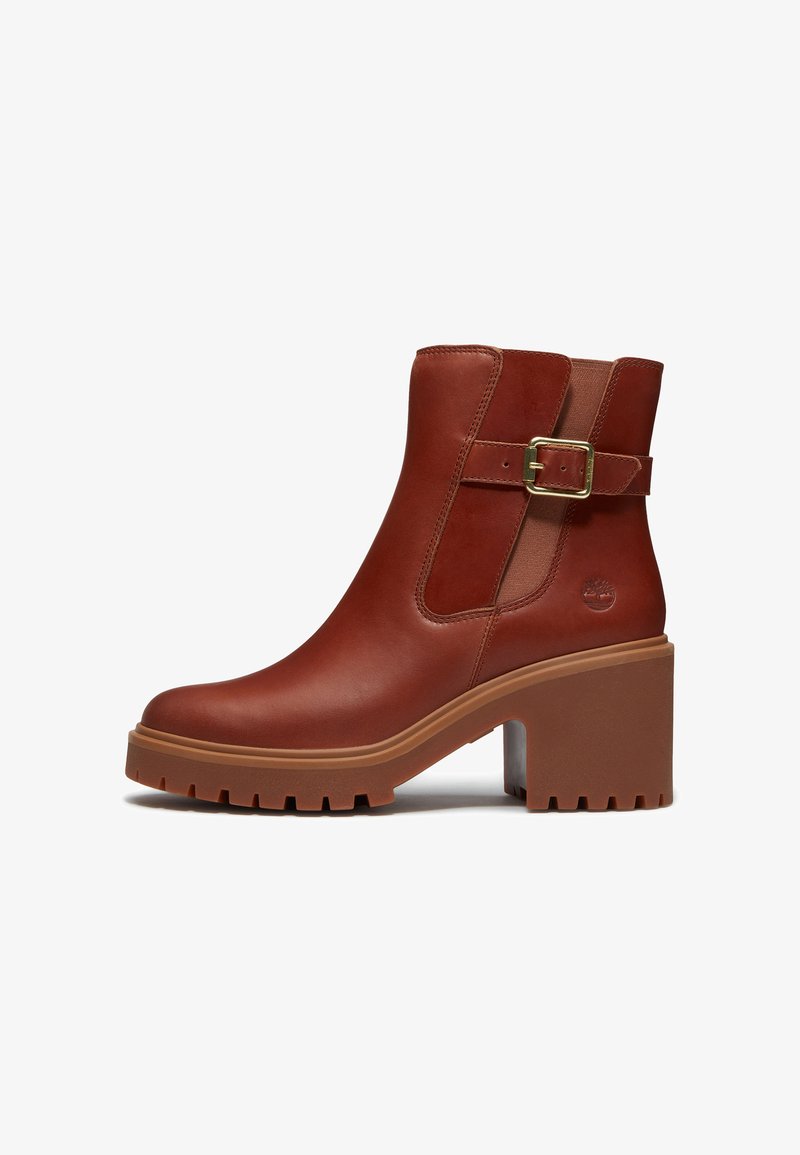 Bottine en cuir marron avec talon bloc épais, semelle à crampons, bride latérale à boucle, panneau élastique et logo embossé sur le côté.