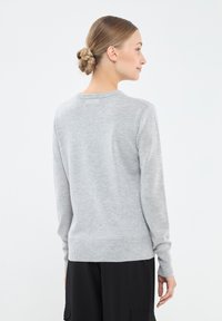 Szary sweter z długimi rękawami, okrągłym dekoltem, ściągaczami przy rękawach i na dole. Miękka faktura, dopasowany krój i minimalistyczny styl.