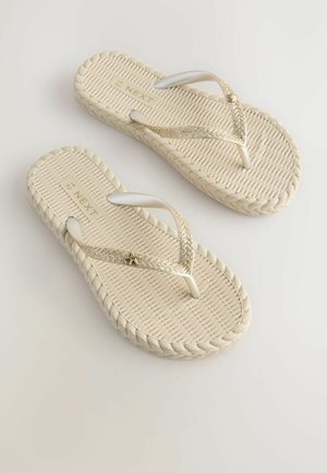 Tongs beiges avec des semelles texturées. Les sangles blanches présentent un accent doré scintillant et un détail en forme d'étoile. Design à bord tressé.