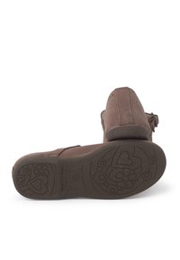 Zapatos de ante marrón con puntera redondeada y suela plana que cuentan con patrones de flores y corazones. El tacón es bajo y tiene un diseño de tipo slip-on con detalles decorativos.