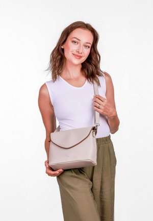 Béžová crossbody taška vyrobená z hladkého materiálu se zavíráním na překlopení a hnědým akcentem. Disponuje nastavitelním popruhem a logem na přední straně.