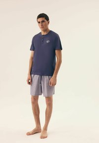 Granatowa bawełniana koszulka t-shirt z zapinanym na guziki designem henley, zestawiona z paskowanymi szortami w odcieniach niebieskiego i białego, z elastycznym pasem.