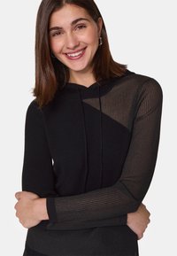Zwarte hoodie met een geribbelde structuur. Het ontwerp heeft sheer zwarte gestreepte mouwen en een iets oversized pasvorm.