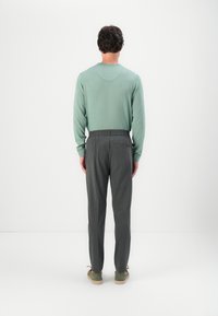Mintgrønn genser med rund hals og grå elastiske bukser med liv. Enkelt design med minimal detaljering og avslappet passform.