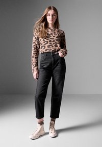 Beige leopardi kuvioitu neule, korkea vyötärö mustat farkut ja beige korkeavartiset lenkkarit, luoden rentoa ja nykyaikaista ilmettä.