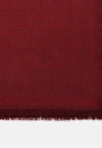 Piena coperta rossa scura con un motivo geometrico testurizzato e bordi sfilacciati, realizzata in materiale morbido per calore e comfort.