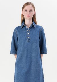 Denimkjole med krage, korte ermer, front knappestolpe og en avslappet passform. Medium blå farge og glatt tekstur.