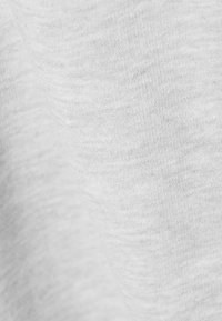 Helles graues Gewebe mit einer glatten, leicht strukturierten Oberfläche, das ein subtil gemustertes Heather-Design aufweist. Nahaufnahme hebt die Materialdetails hervor.