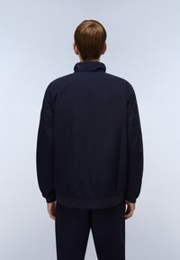 Marinblå jacka med hög krage, elastiska ärmslut och slät textur, med en avslappnad passform och minimalistisk design.