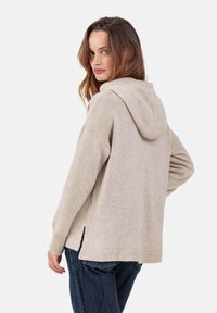 Hellbeiger Hoodie mit lockerem Sitz, großer Kapuze, seitlichen Schlitzen, gerippten Bündchen und weicher Textur.