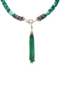Collier vert avec une lanière en tissu à motifs, des accents de perles, des éléments en métal doré et un long pompon vert fait de couches de fils de perles.