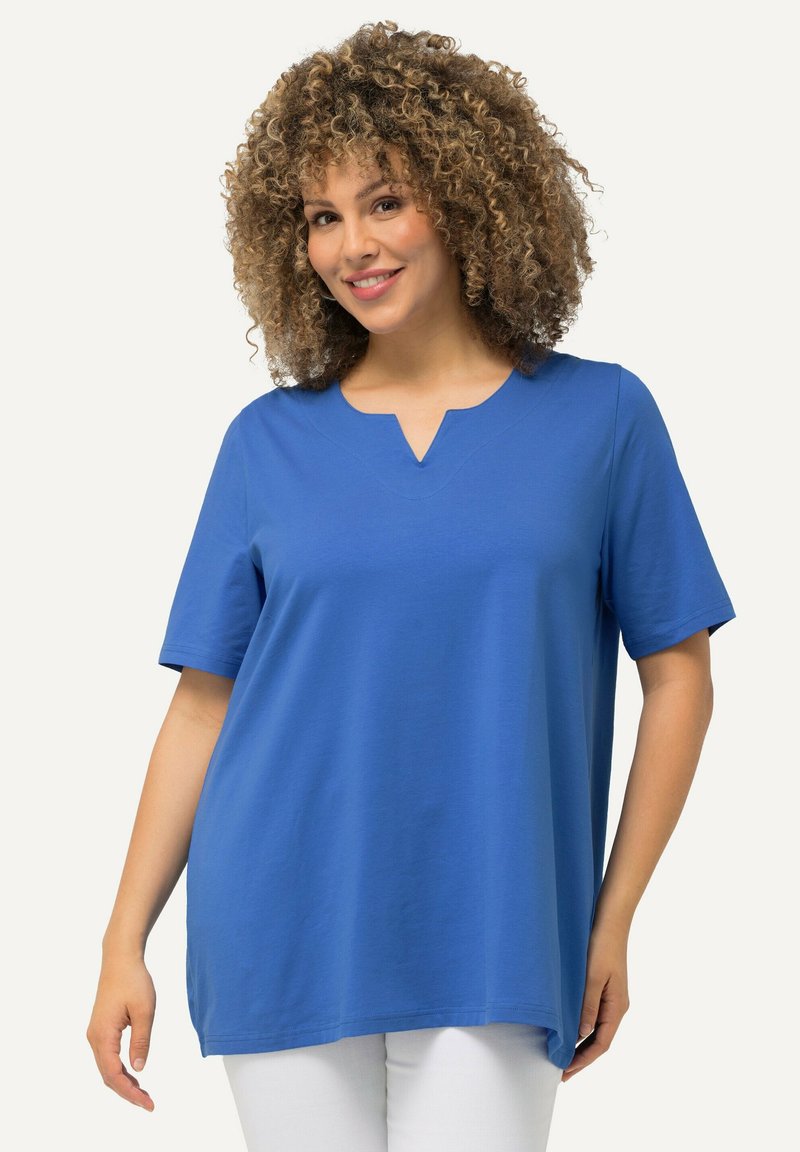 Modrý top s krátkým rukávem a výstřihem do V, vyrobený z jemné látky, s uvolněným střihem a bočními rozparky.