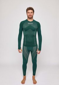 T-shirt de sport à manches longues verte et leggings de Snocks avec un tissu texturé, des coutures blanches contrastantes et une coupe ajustée pour le confort.