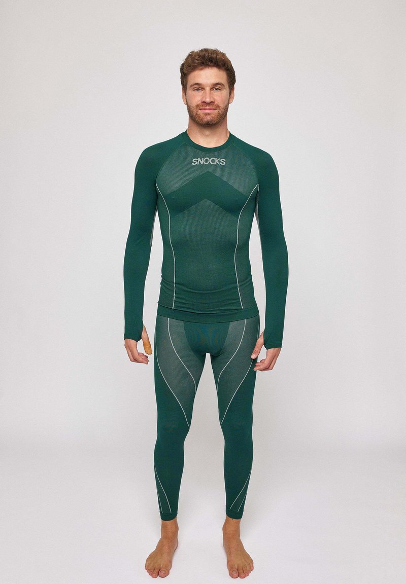 T-shirt de sport à manches longues verte et leggings de Snocks avec un tissu texturé, des coutures blanches contrastantes et une coupe ajustée pour le confort.