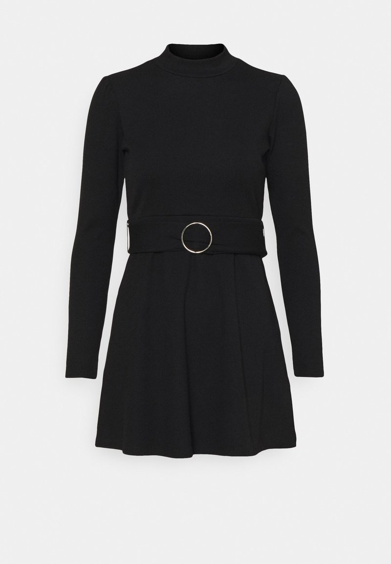 Robe noire en tricot à manches longues avec un col montant, une jupe évasée et une large ceinture ornée d'une grande boucle circulaire argentée à la taille.