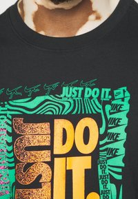 Black cotton T-shirt featuring bold, multicolored graphics of "JUST DO IT." Includes green, orange, and pink accents with various font styles.