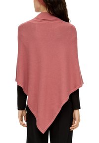 Roze, gebreide poncho met een ruitpatroon en een open voorkant. De randen zijn licht afgewerkt. Gekocht over een zwart langemouwtop en een broek.