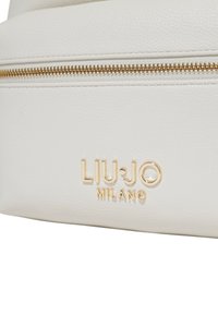 Borsa bianca in pelle con un logo in tonalità oro ben visibile e dettagli con cerniera, dotata di una superficie testurizzata e bordi puliti e arrotondati.