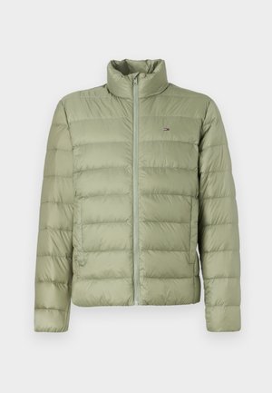 Casaco puffer verde claro com gola alta, costura horizontal, fecho na frente e um pequeno logo no lado esquerdo do peito. Textura suave e acolchoada.