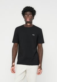 Zwarte T-shirt met korte mouwen van katoen, met een klein wit "BOSS" logo op de borst, voorzien van een ronde halslijn en een relaxte pasvorm.