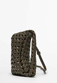 Vävd mörkgrön läderväska med rektangulär form, tunn justerbar rem, texturerad yta och öppen toppdesign.